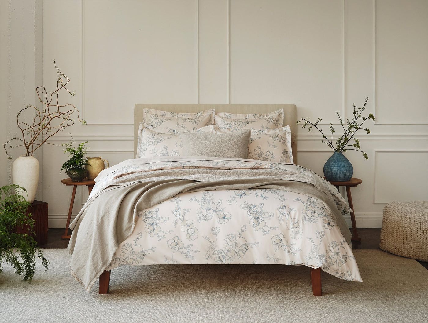 Ivory matelasse sham with soft blue-grey floral print, styled on a made bed.