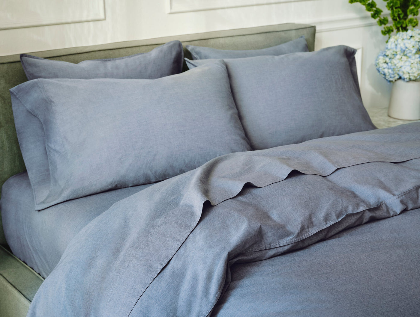 Coyuchi Crinkled Percale pillowcases in slate blue, styled on a made bed with duvet.