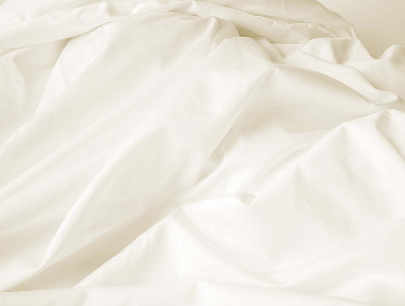 Close-up of ivory Coyuchi Heirloom Sateen duvet cover showing soft fabric drape and sheen.