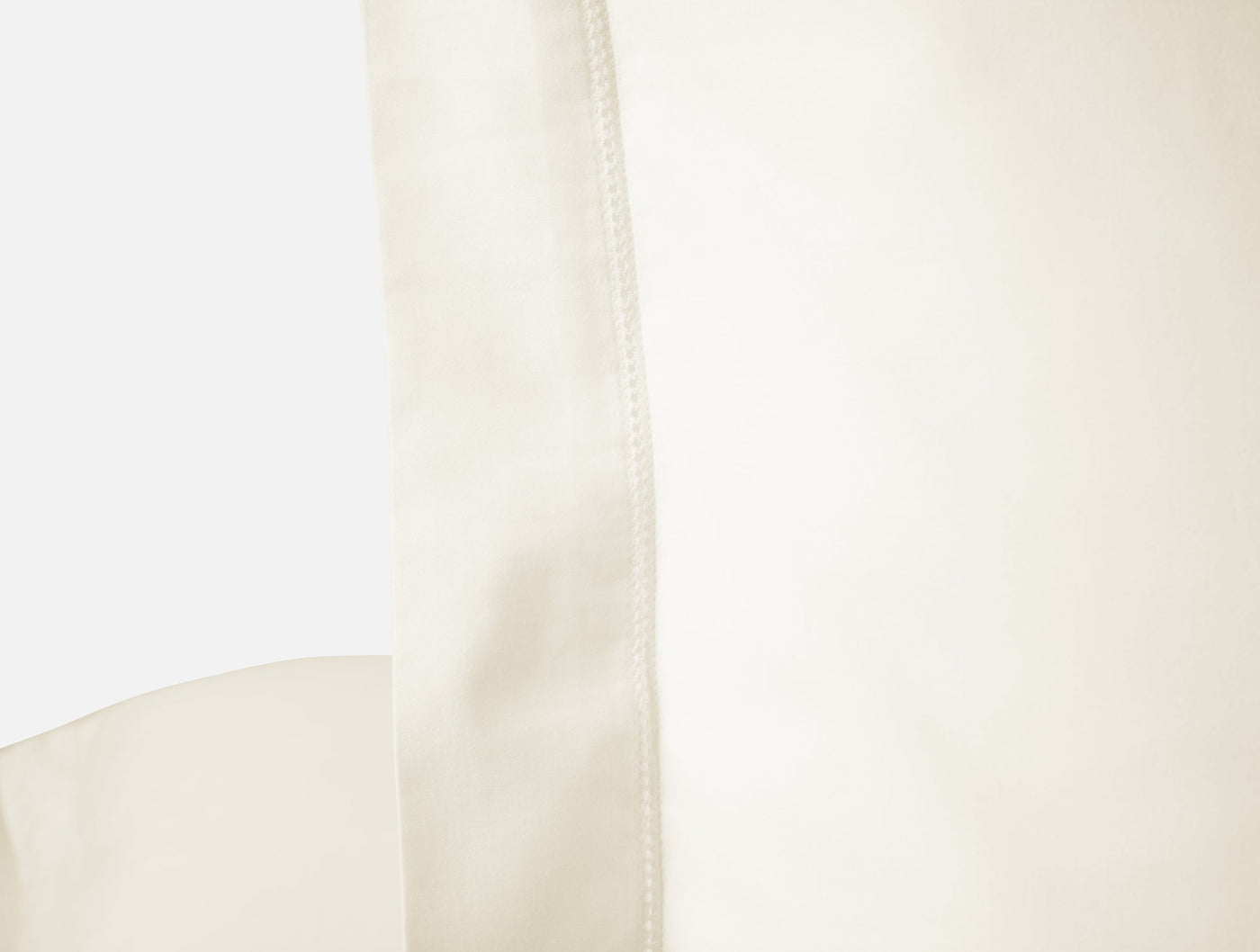 Close-up of ivory sateen pillow sham hem with topstitched edge detail.