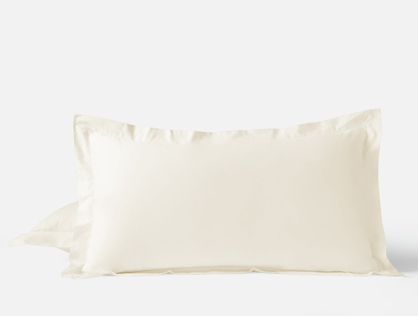 Close-up of ivory Coyuchi Heirloom Sateen pillow sham showing ruffled edge detail.