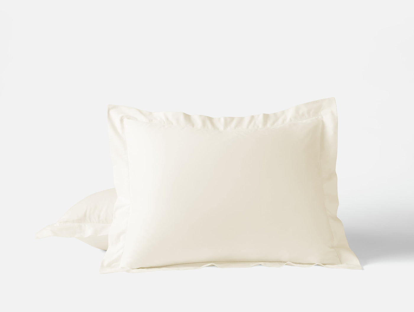 Ivory sateen pillow sham with flange border, slightly gathered fabric visible at base.