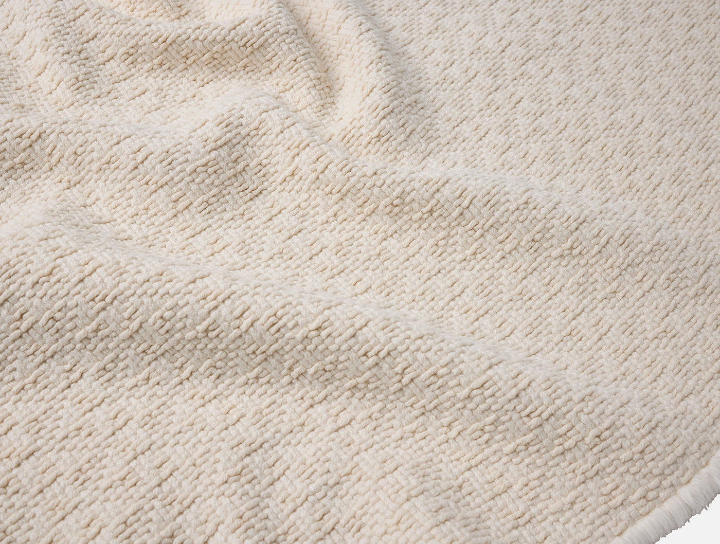 Close-up of Coyuchi Honeycomb bath rug in ivory, showing textured terry weave detail.