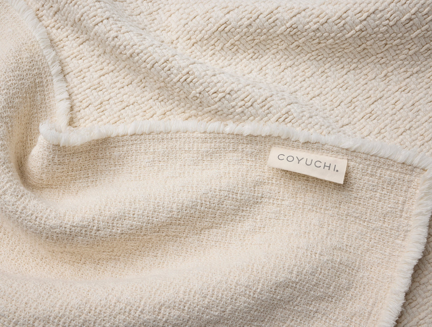 Close-up of ivory Coyuchi bath rug showing honeycomb texture and woven label.