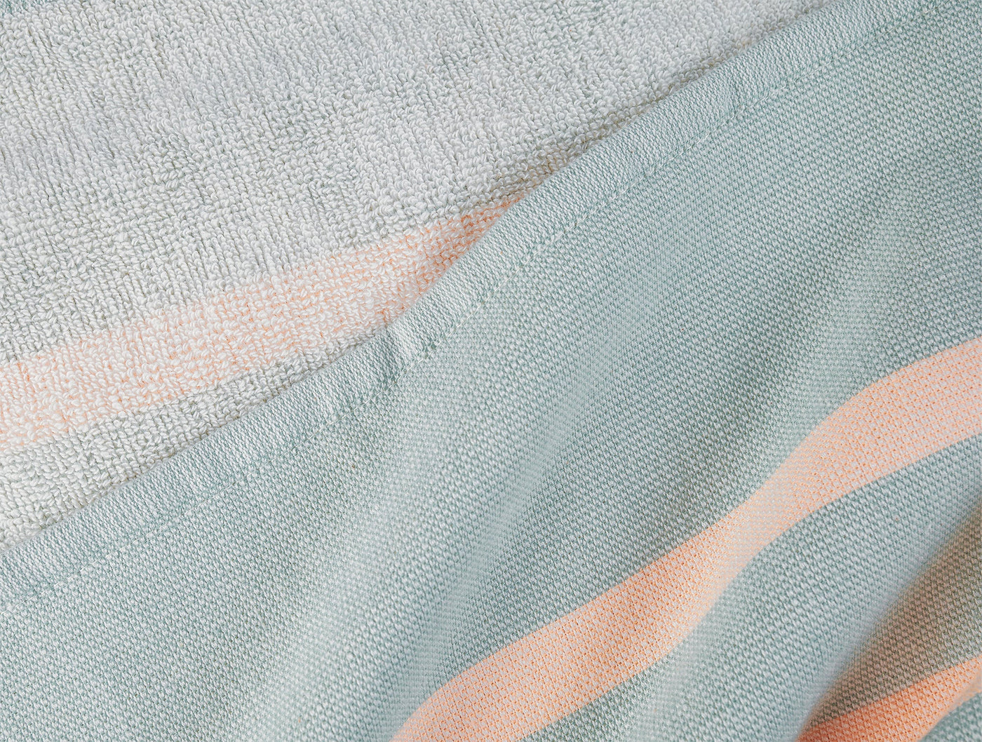 Close-up of Coyuchi Laguna beach blanket hem, showing seafoam and blush stripe weave detail.