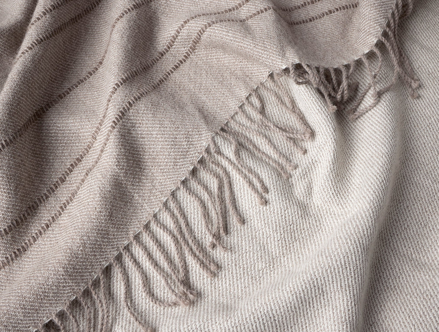 Close-up of Coyuchi Lima throw fringe edge, showing soft alpaca weave with subtle stripe detail.