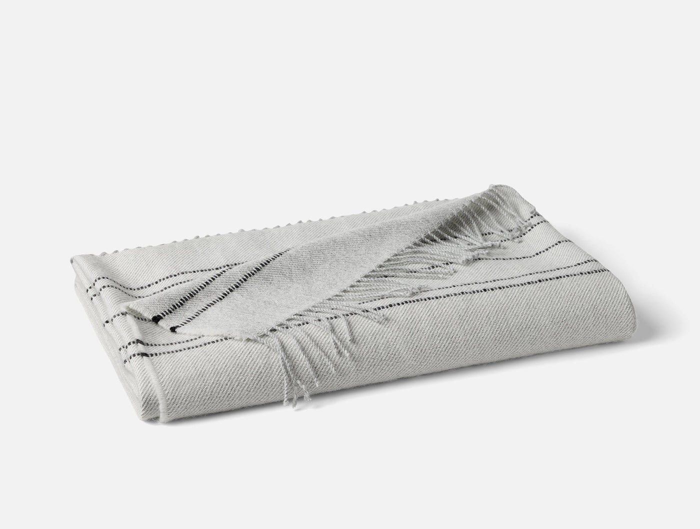 Folded silver and charcoal striped alpaca throw with fringe hem detail.