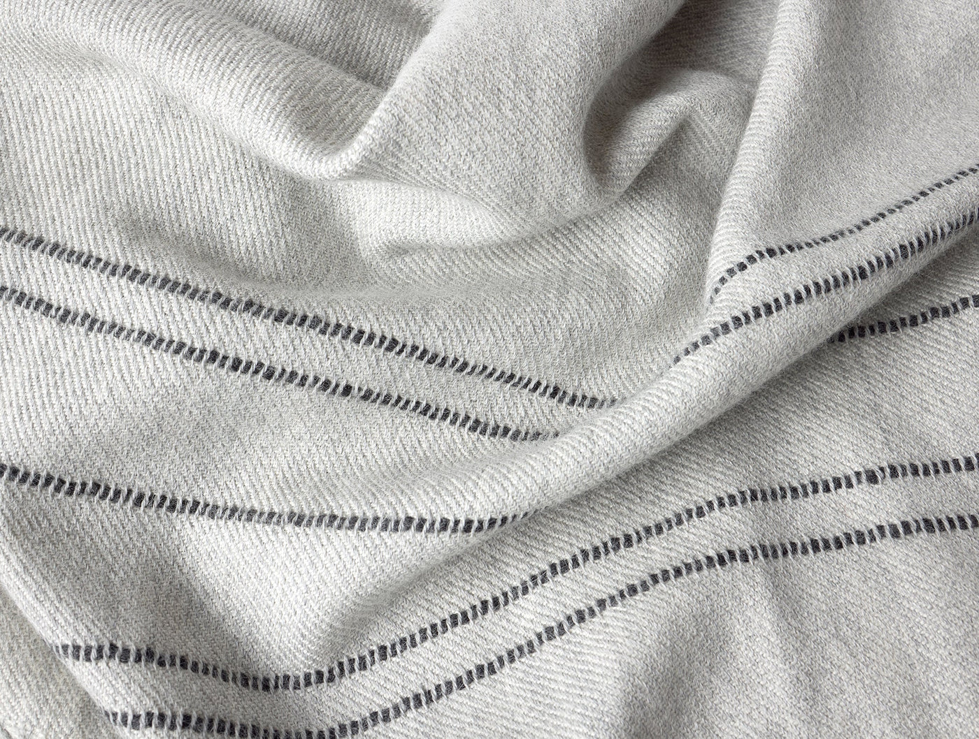Close-up of ivory alpaca fabric with charcoal pinstripes and visible woven texture.
