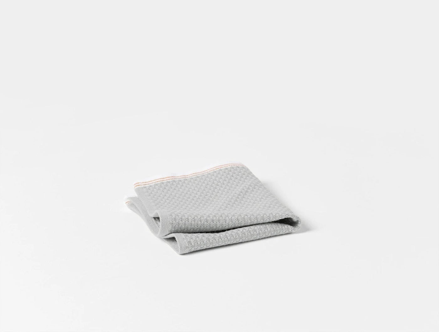 Close-up of folded silver grey waffle-weave bath sheet showing textured surface detail.