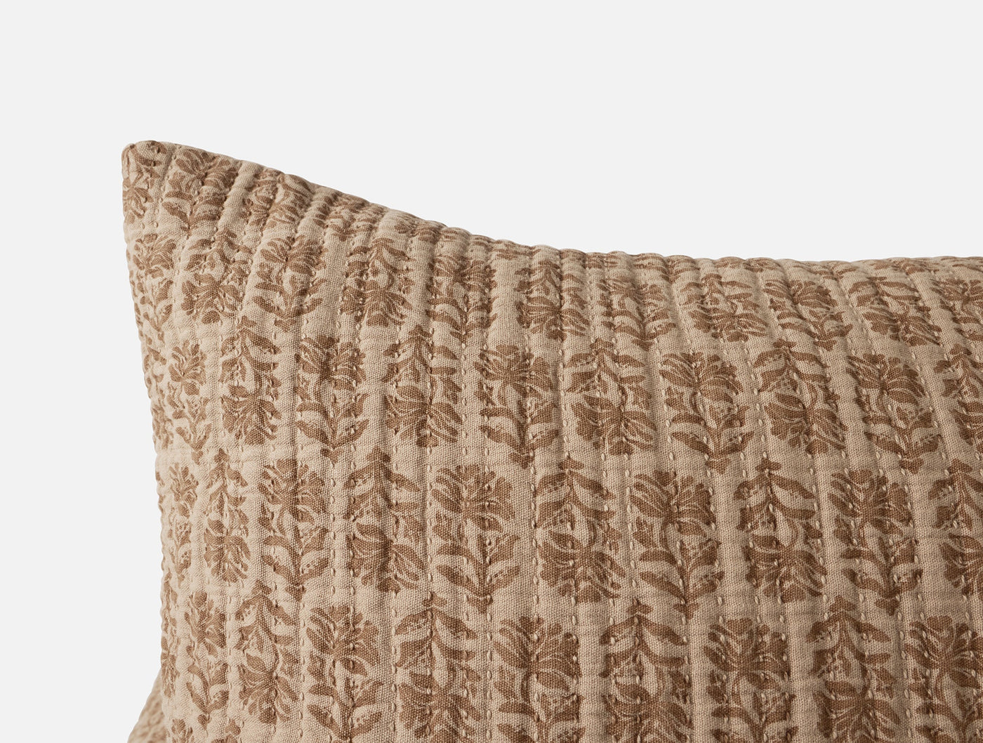 Close-up of Coyuchi Mirada Matelassé sham corner, sand with block-print floral pattern.