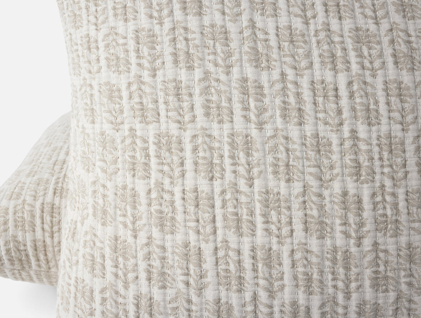 Close-up of Coyuchi Mirada Matelassé sham showing taupe floral block-print texture on ivory cotton.