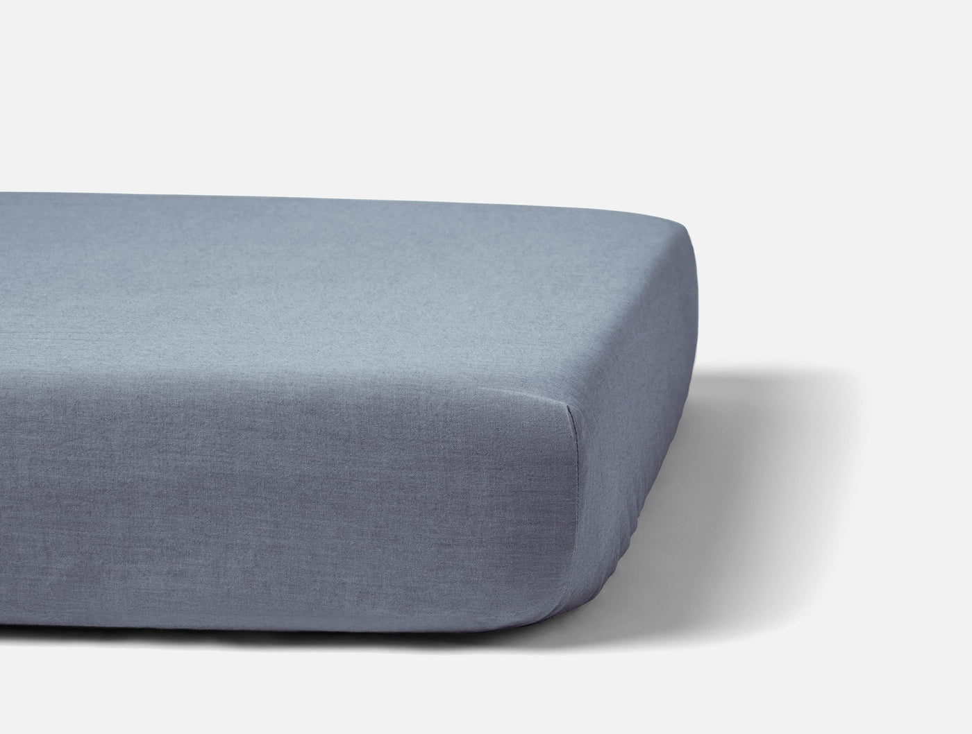 Coyuchi Crinkled Percale fitted sheet in slate blue, shown fitted tautly on a mattress.