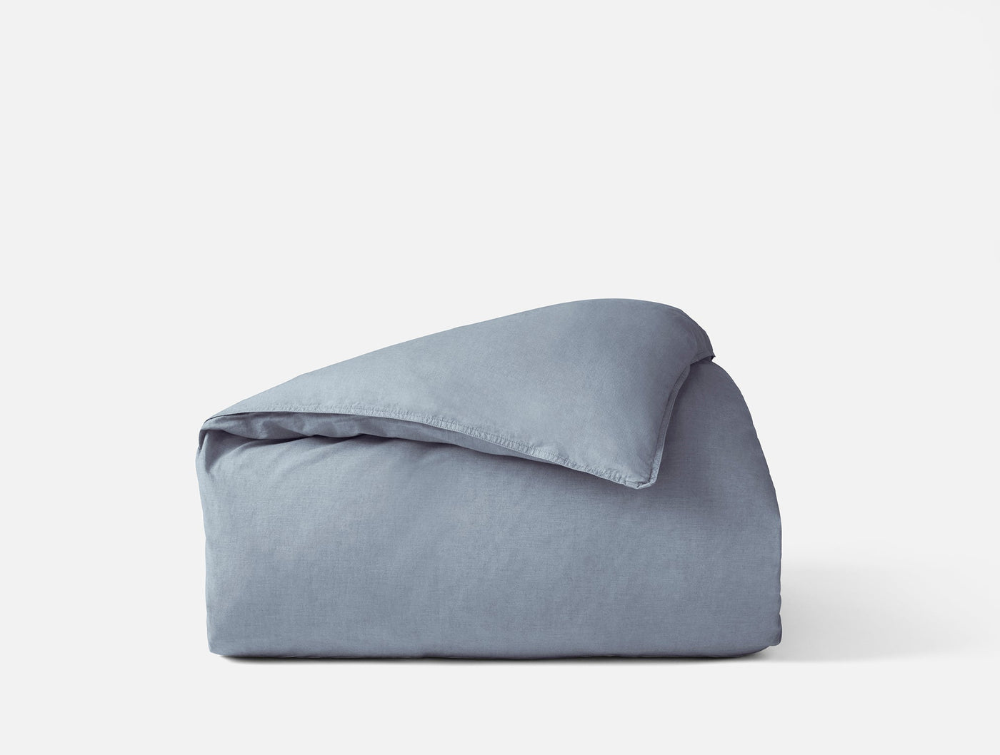 Close-up of folded Coyuchi Crinkled Percale duvet cover in slate blue with relaxed texture.