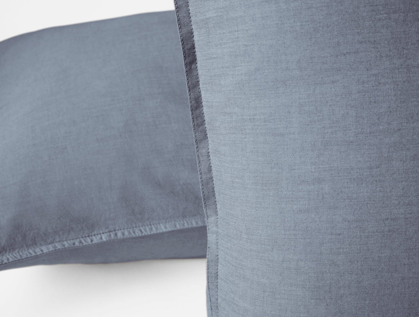 Close-up of slate blue crinkled percale pillow sham showing hem stitching detail.