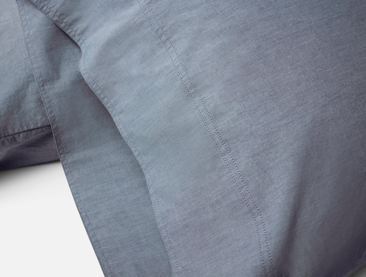 Close-up of Coyuchi Crinkled Percale pillowcase hem stitching in slate blue.