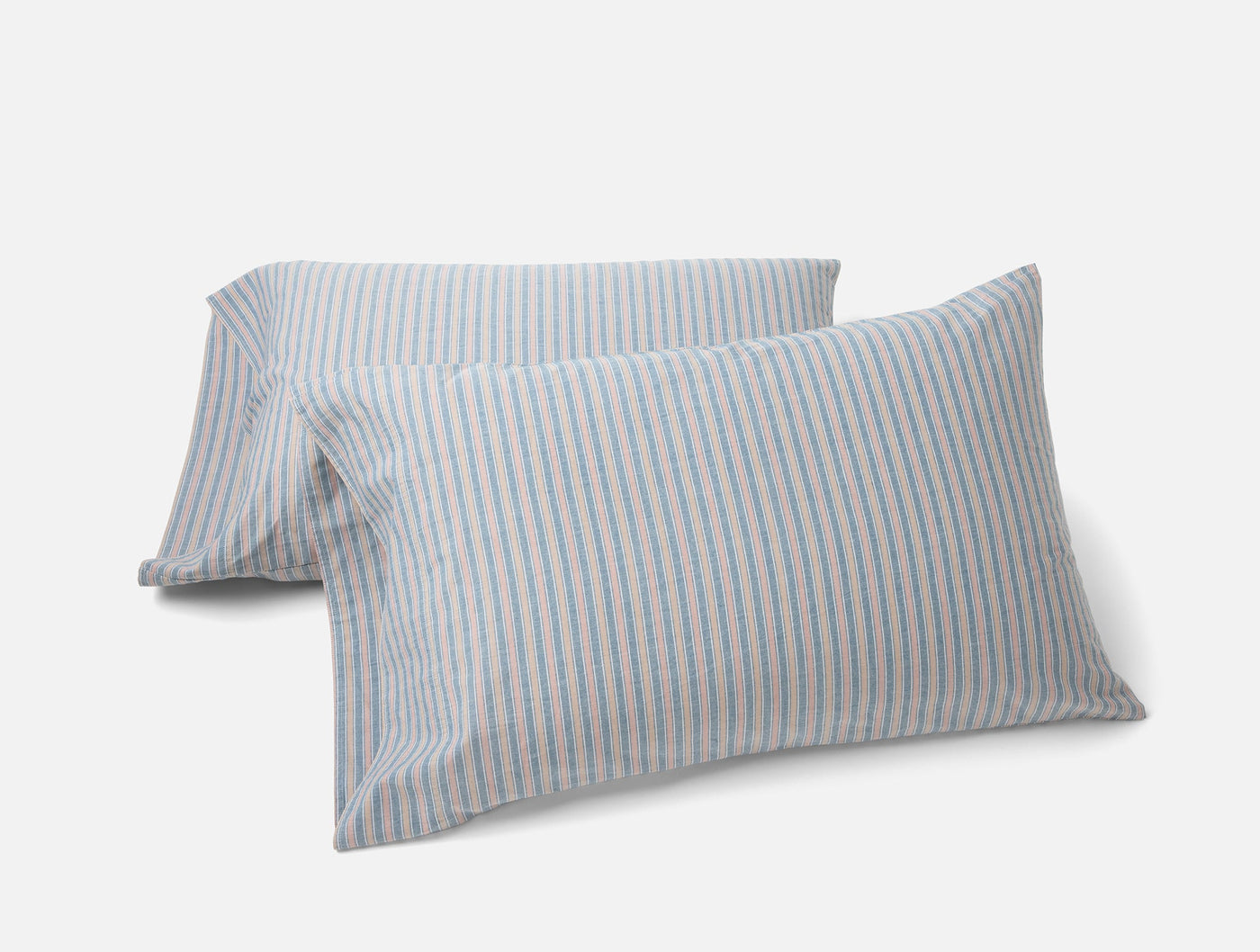 Two Coyuchi Crinkled Percale pillowcases with blue and pink thin stripes on white.