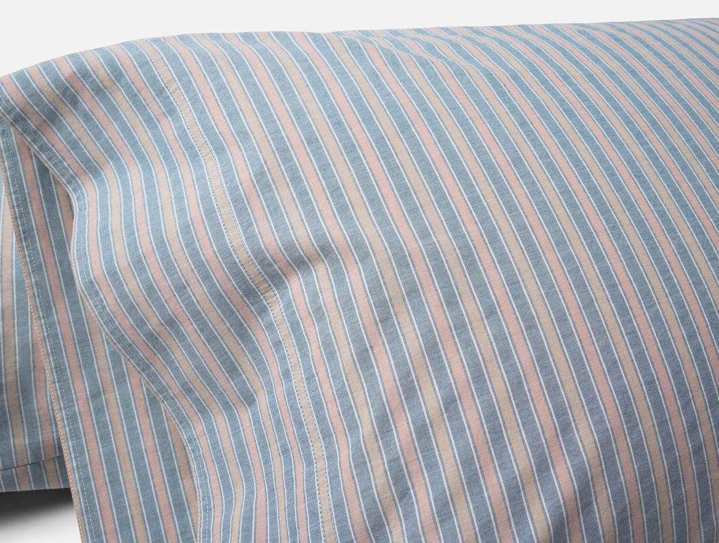 Close-up of Coyuchi Crinkled Percale pillowcase in blue, blush, and ivory stripes.