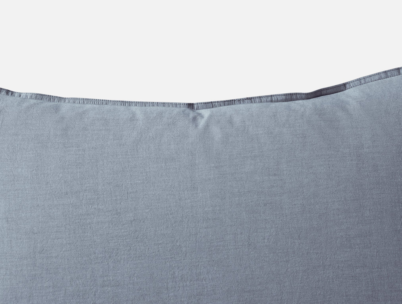 Close-up of Coyuchi Crinkled Percale sham top edge with contrast blanket-stitch trim detail.