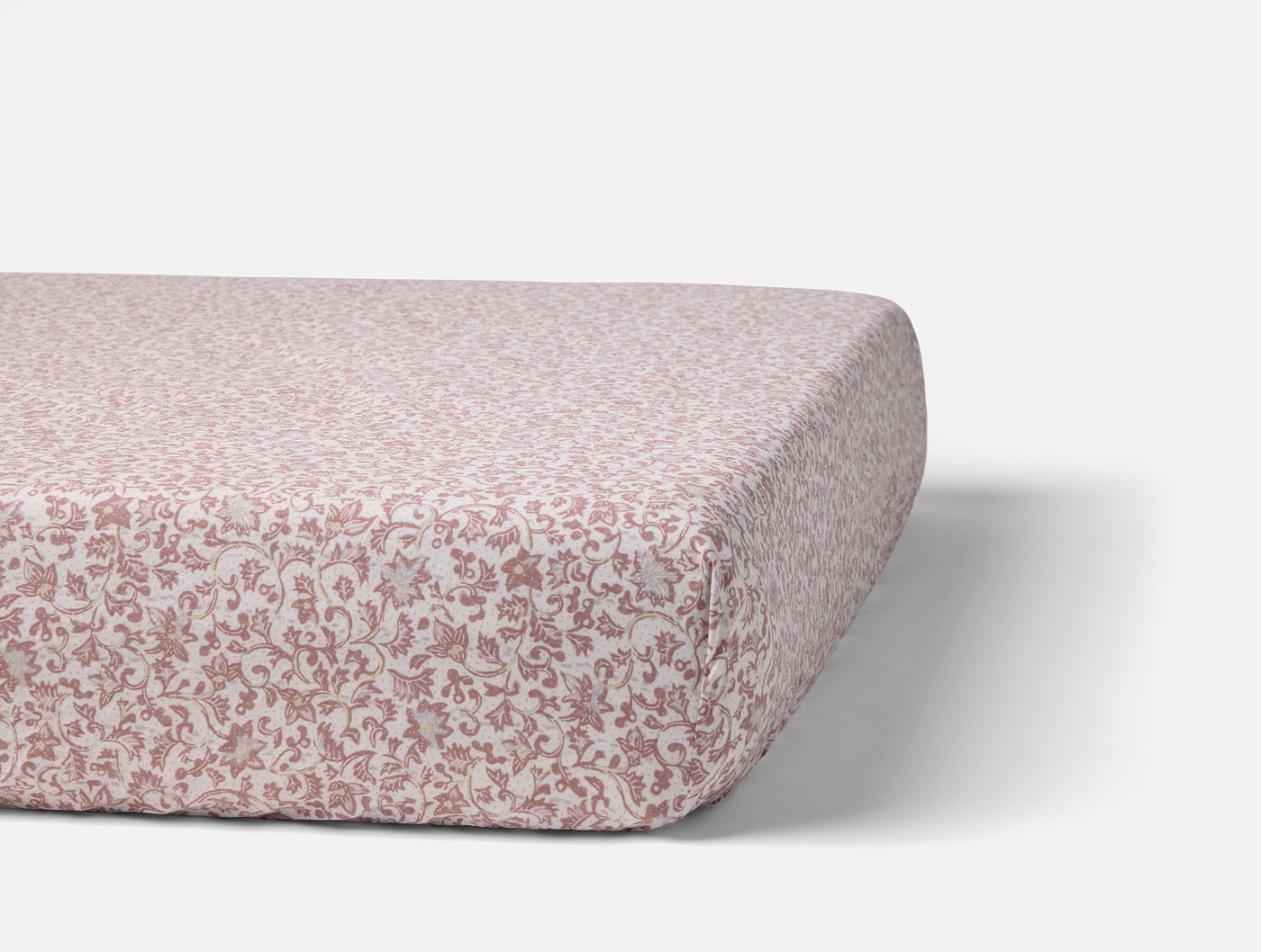 Coyuchi Print Percale fitted sheet in dusty rose floral pattern on mattress.