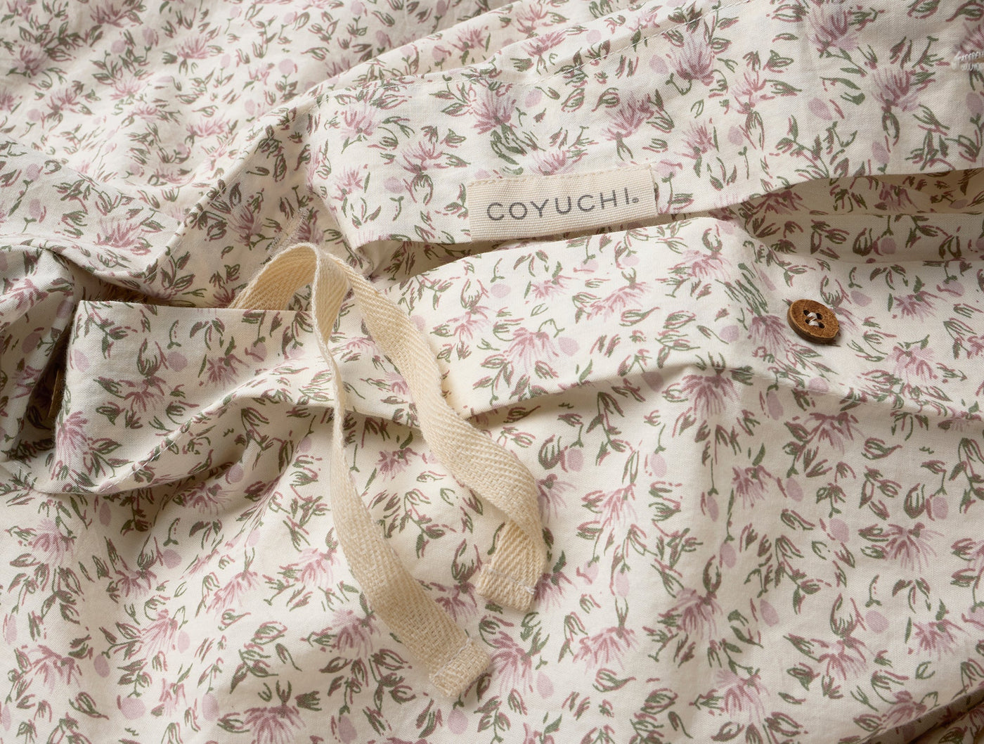 Close-up of Coyuchi duvet cover interior label with ivory ties and pink floral print detail.