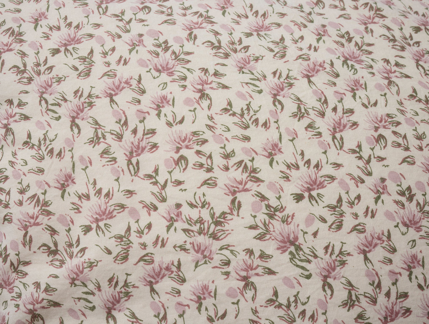 Close-up of Coyuchi Print Percale pillowcase fabric with pink floral and olive leaf pattern.