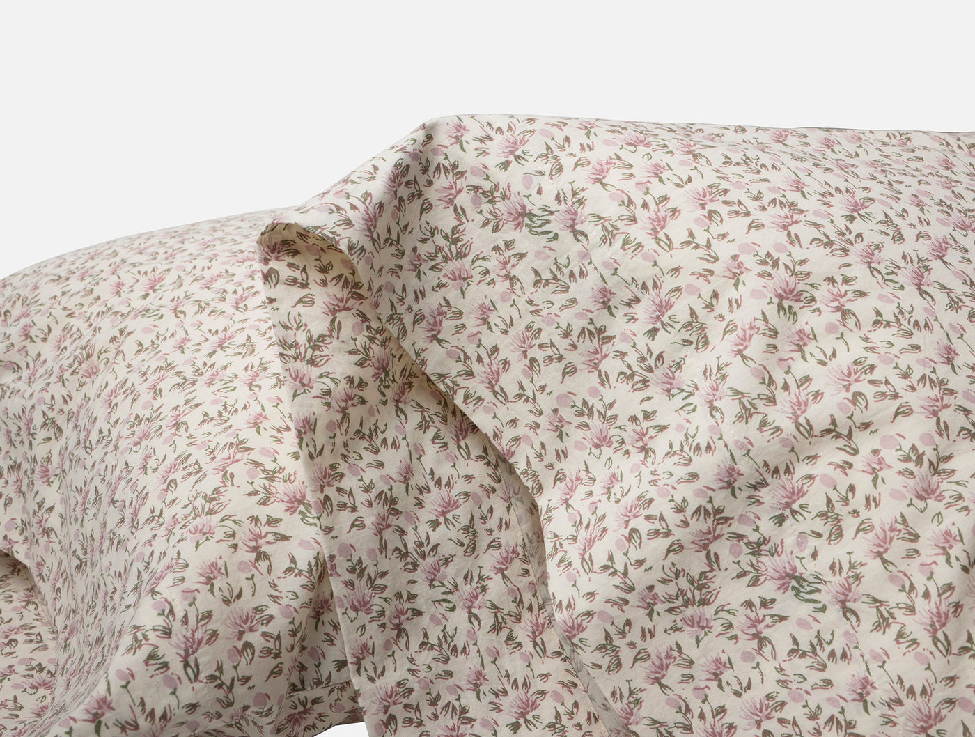 Close-up of Coyuchi ivory percale pillowcase with delicate pink floral and green leaf print.