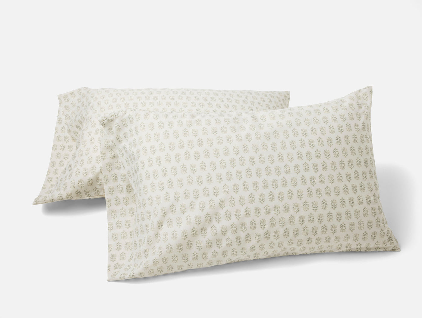 Pair of Coyuchi ivory percale pillowcases with sage botanical block print pattern.