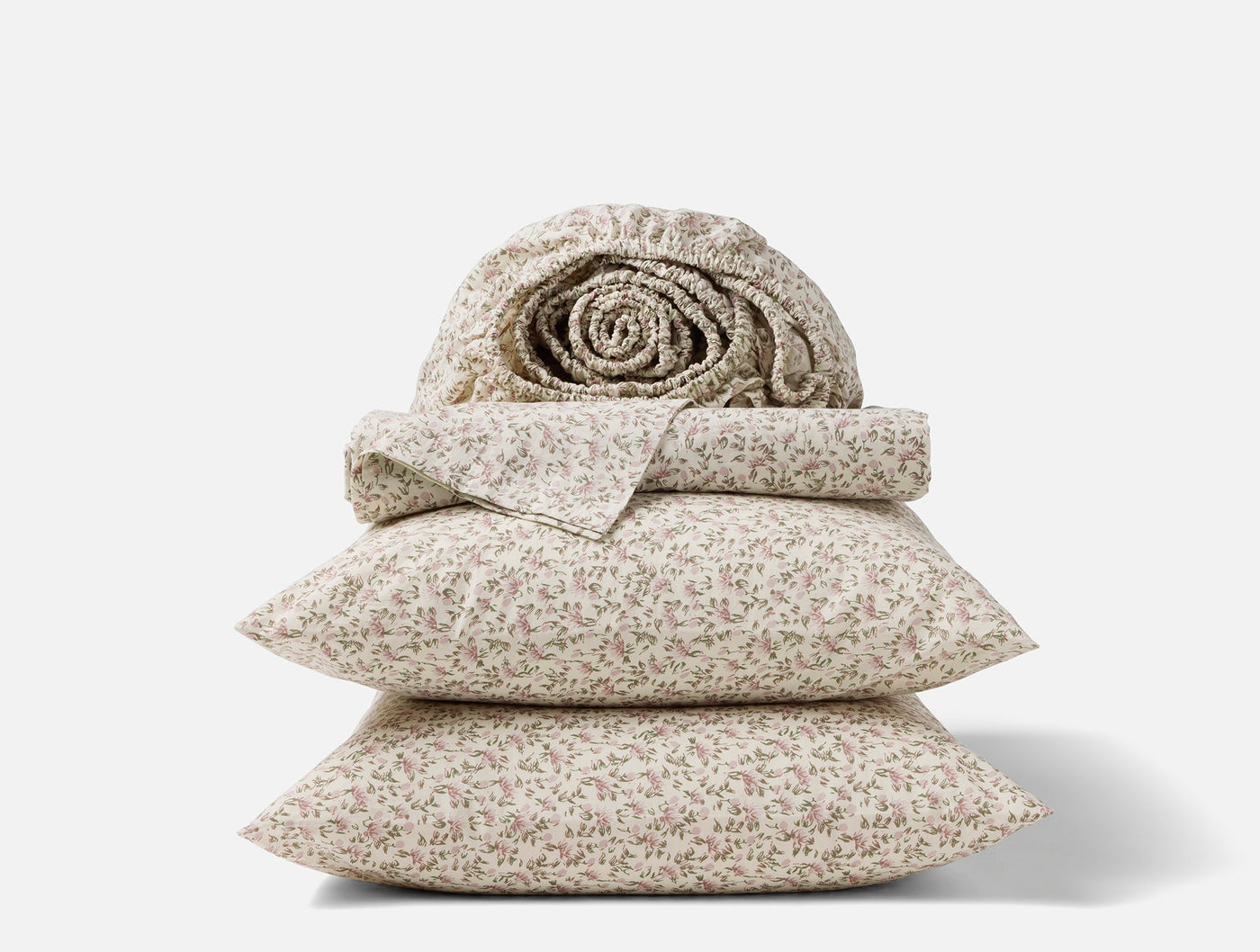 Close-up stack of Coyuchi Print Percale sheet set with delicate floral pattern in ivory.