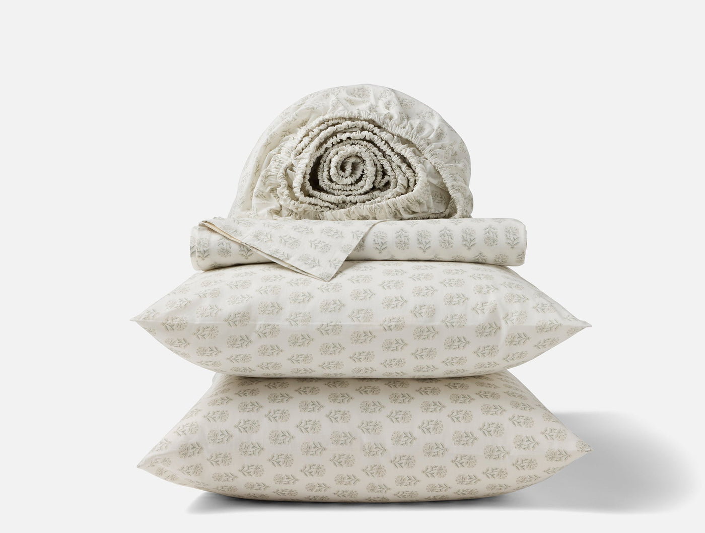 Close-up stack of Coyuchi Print Percale sheet set in ivory with subtle botanical print.