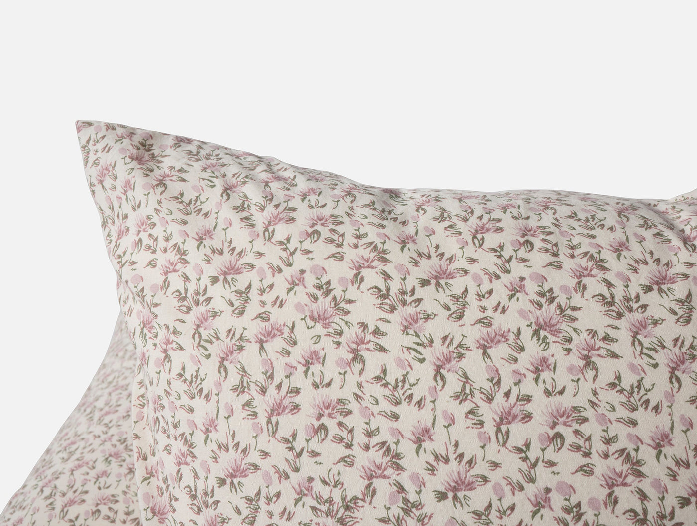 Close-up of Coyuchi Print Percale pillow sham corner with pink floral pattern on ivory.
