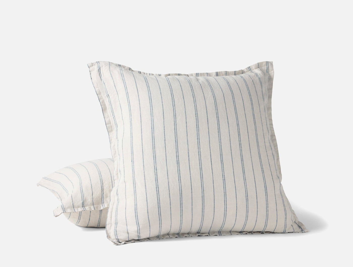 Close-up of Coyuchi Relaxed Linen pillow covers in white with blue pinstripes, ruffled edges.