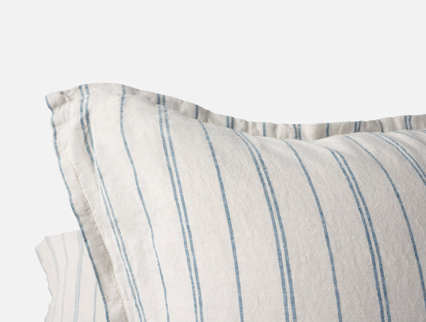 Close-up of Coyuchi Relaxed Linen pillow cover corner with blue ticking stripes and frayed trim.