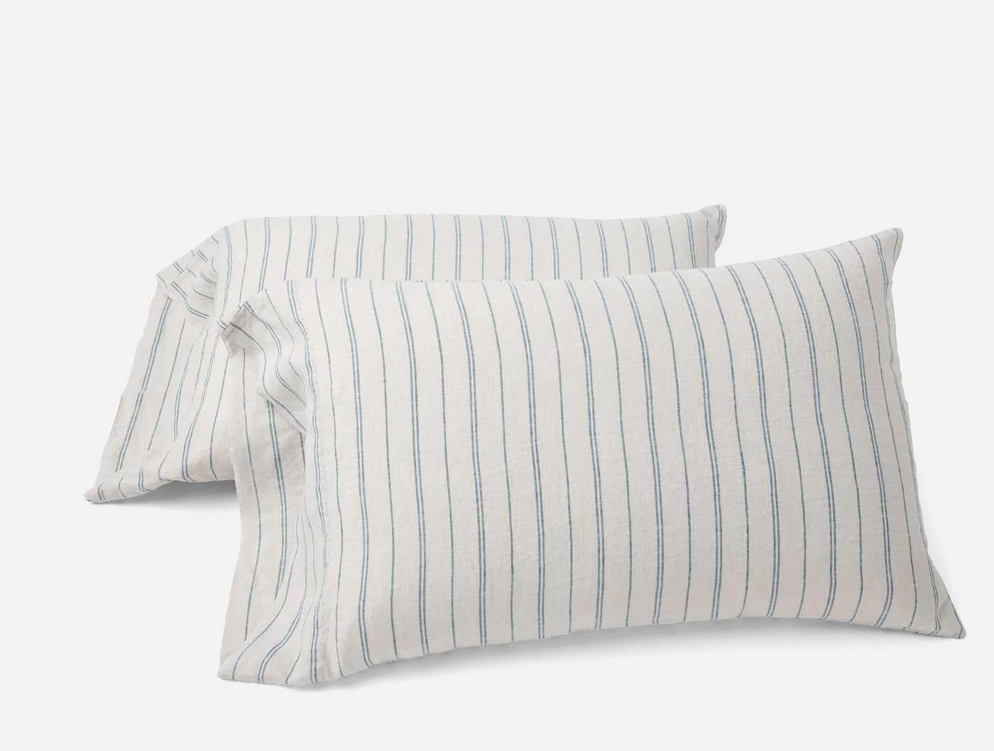 Pair of Coyuchi Relaxed Linen pillowcases with blue pencil stripes on ivory, stacked at an angle.