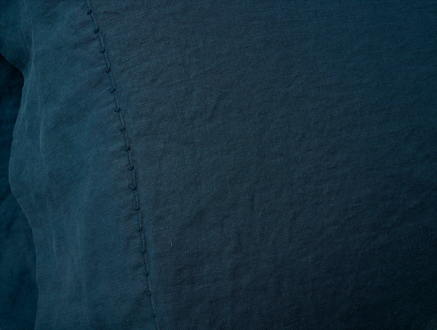 Close-up of Coyuchi Relaxed Linen pillowcase in deep teal, showing hem stitching detail.
