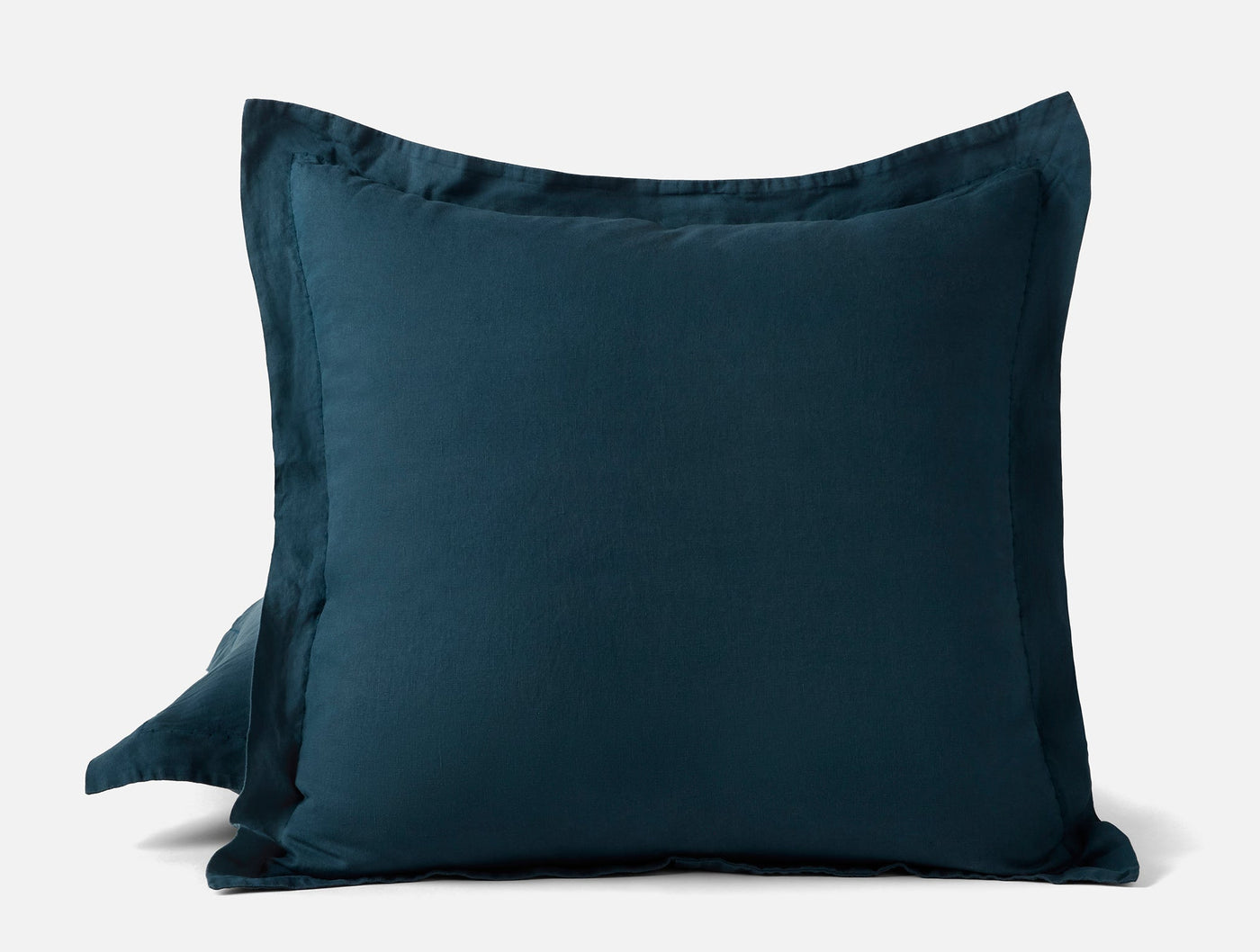 Close-up of Coyuchi Relaxed Linen sham pair in deep teal with a tailored flange border.