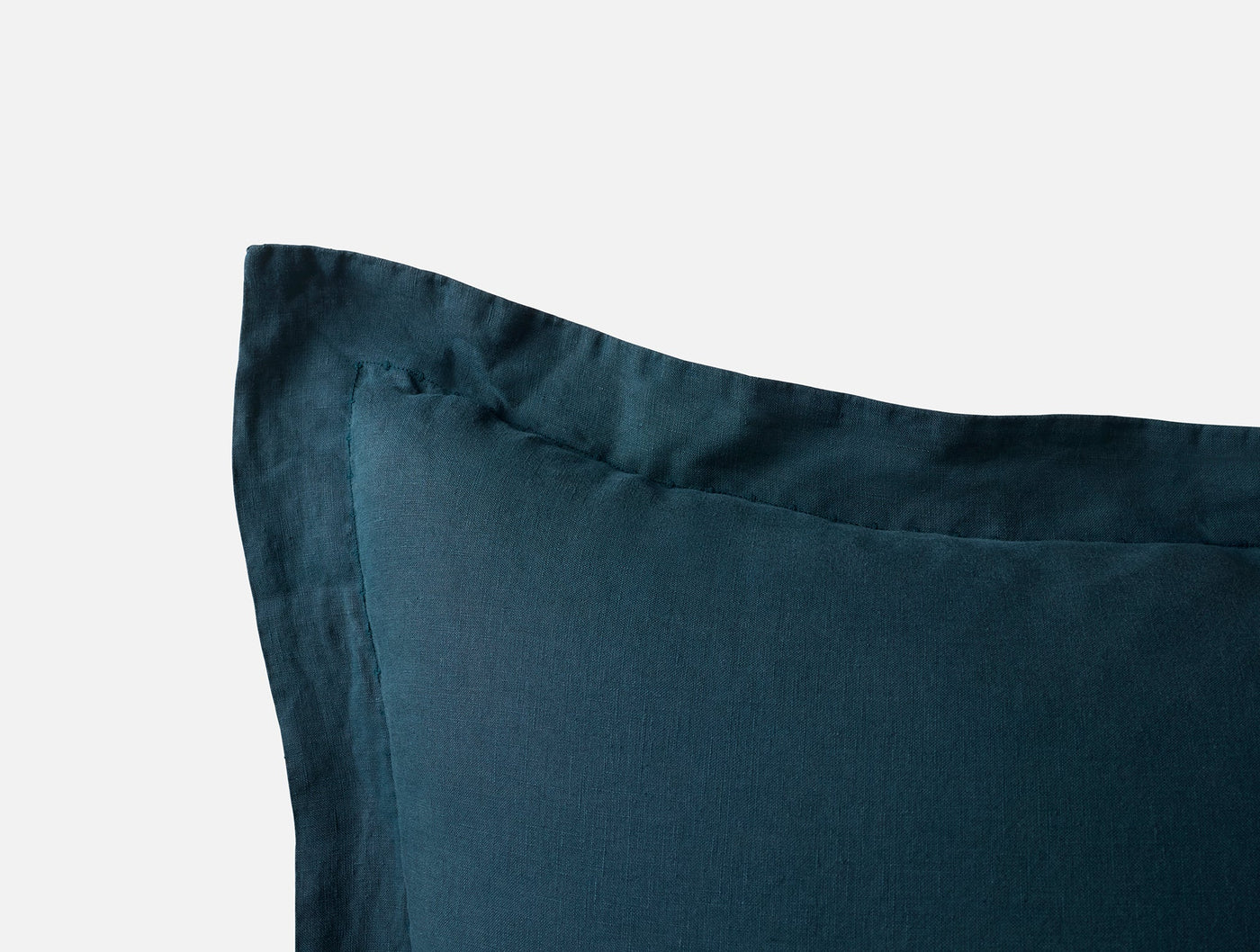 Close-up of Coyuchi Relaxed Linen sham corner in deep teal, showing flange detail.
