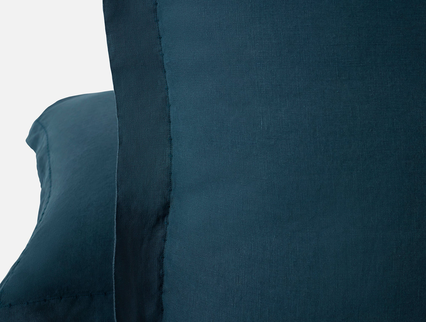 Close-up of Coyuchi Relaxed Linen sham edge in deep teal, showing raw hem detail.