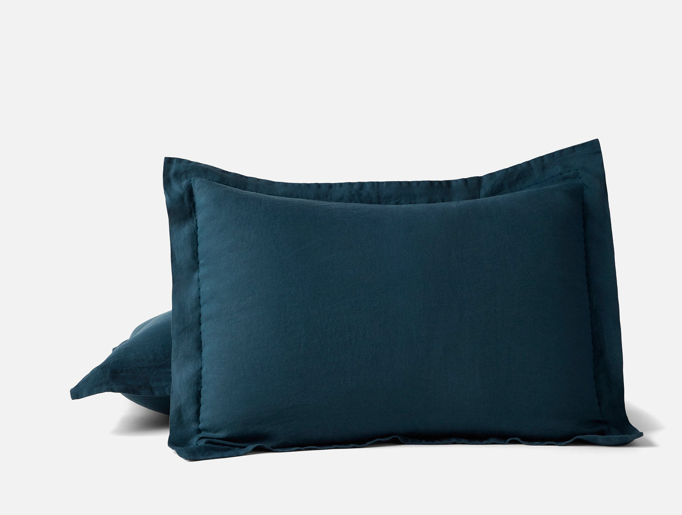 Pair of Coyuchi Relaxed Linen shams in deep teal, showing flange edge detail.