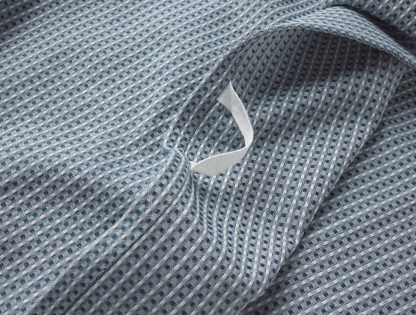 Close-up of slate blue waffle-weave kitchen towel with white Coyuchi label visible.