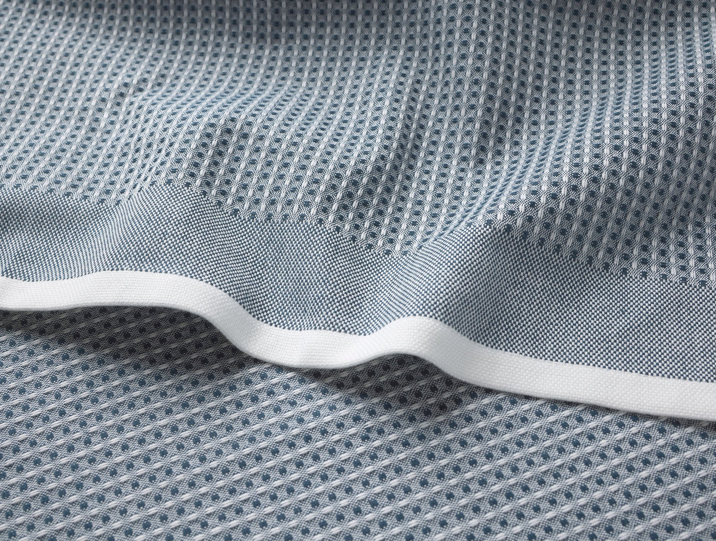 Close-up of slate blue waffle-weave kitchen towel with white hemmed edge.