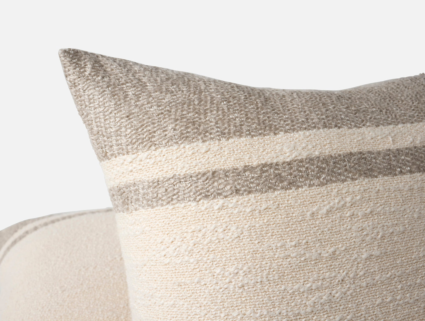 Close-up of Coyuchi Pampas pillow corner showing ivory boucle texture with taupe stripe detail.