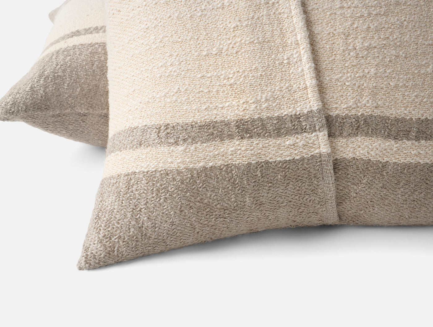 Close-up of Coyuchi Pampas pillow corners showing taupe stripe detail on ivory boucle fabric.