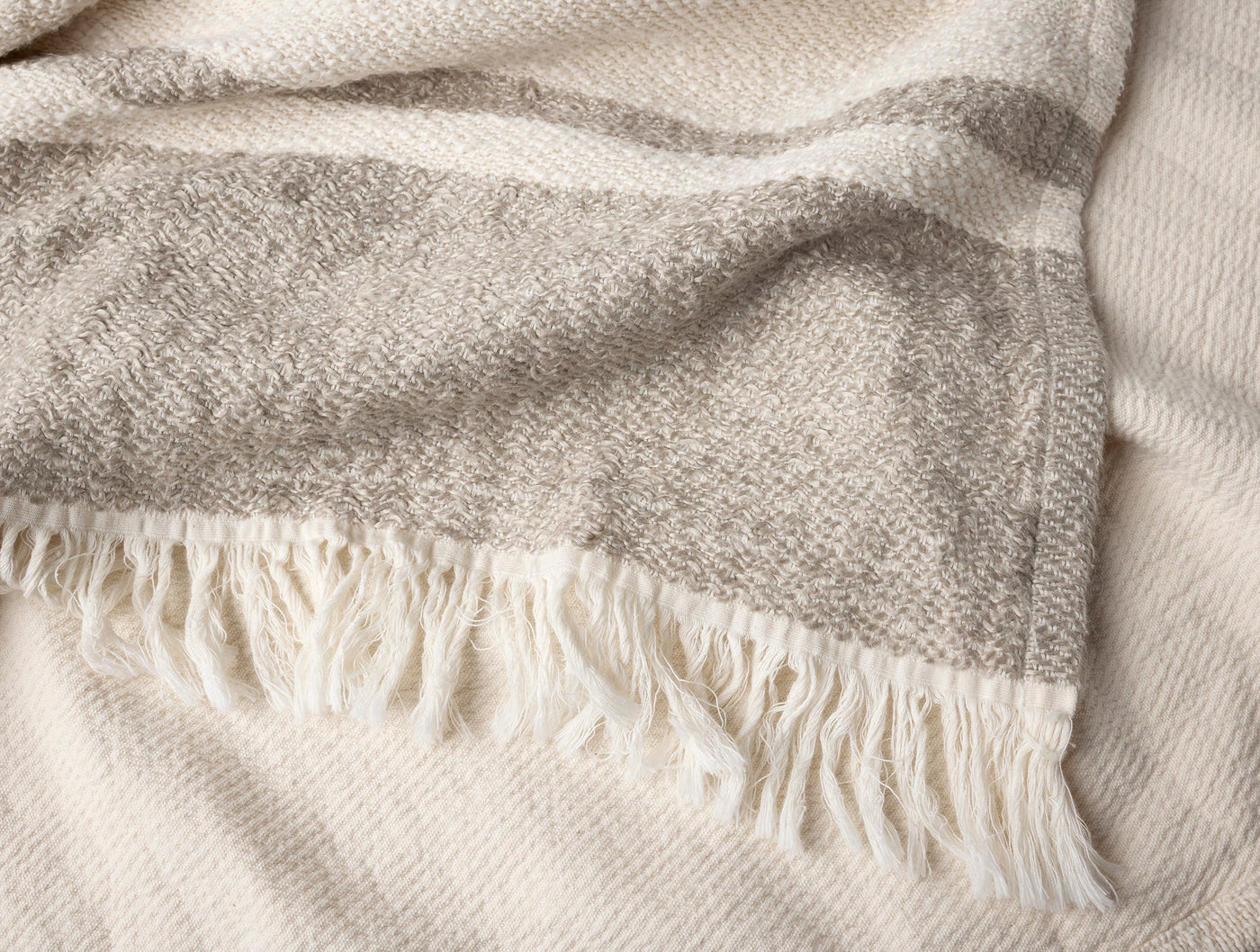 Close-up of Coyuchi Pampas throw fringe and woven texture in ivory and grey.