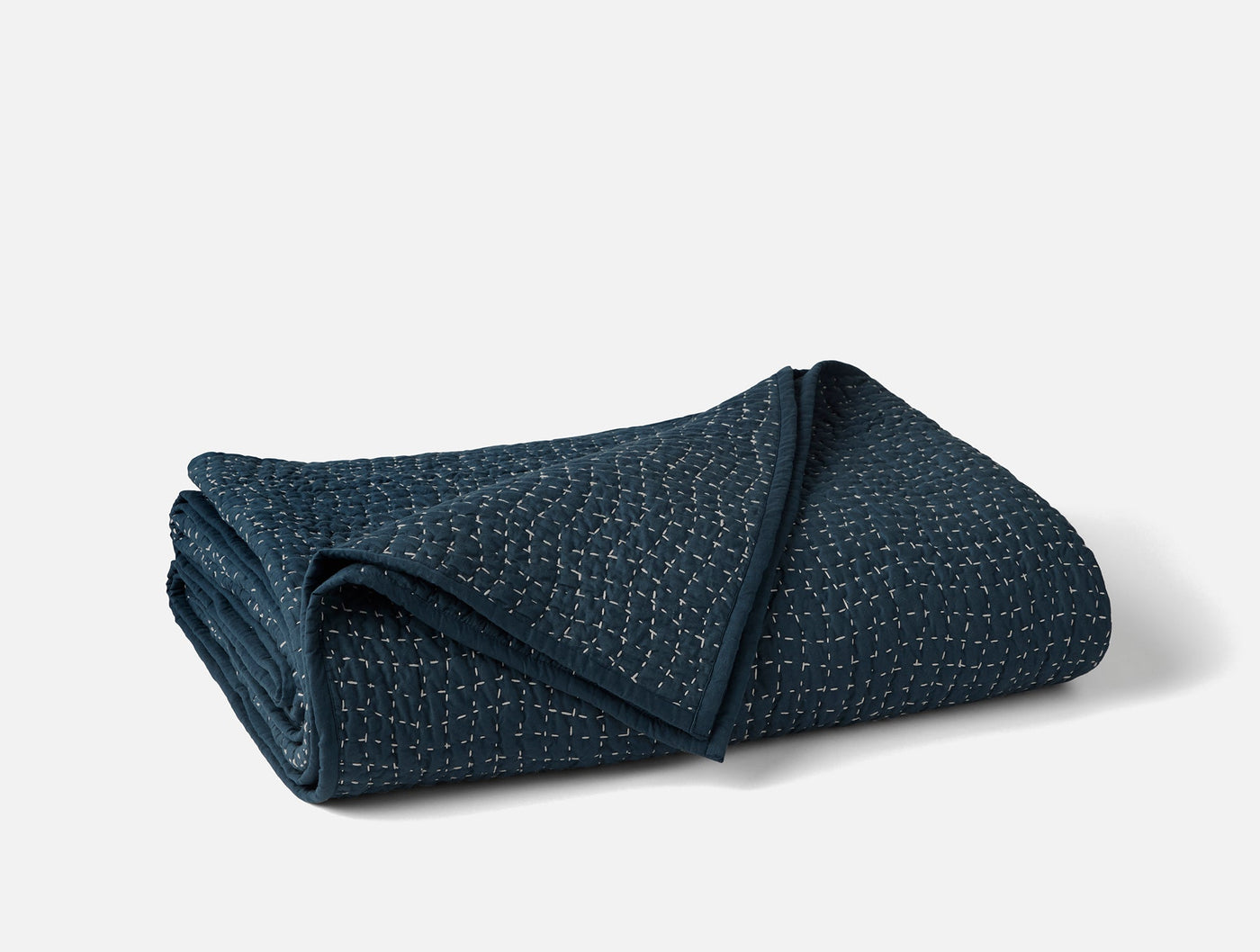 Coyuchi Pebbled Handstitched quilt folded, showing navy textured weave and stitched edges.