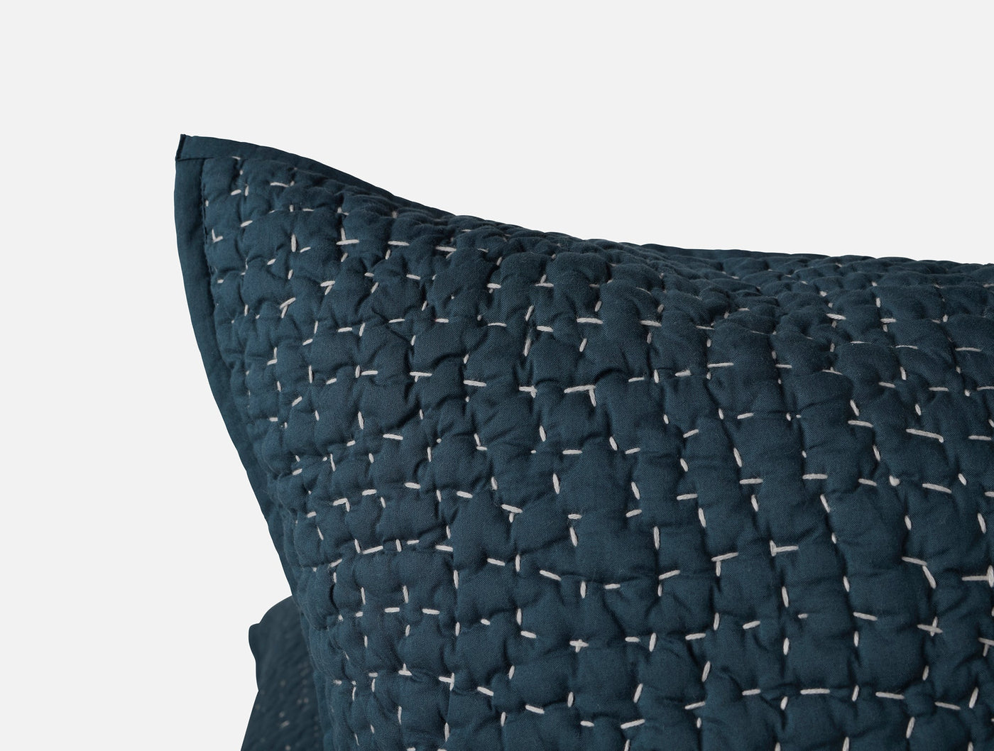 Close-up of navy blue quilted sham corner showing handstitched pebbled texture detail.