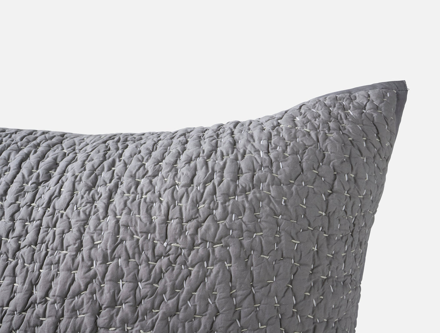 Close-up of slate grey quilted sham showing irregular pebbled handstitch texture detail.