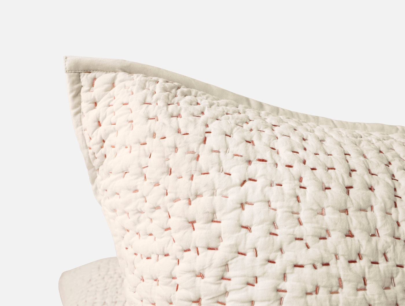 Corner detail of ivory Coyuchi Pebbled Handstitched sham showing woven texture and blush stitching.