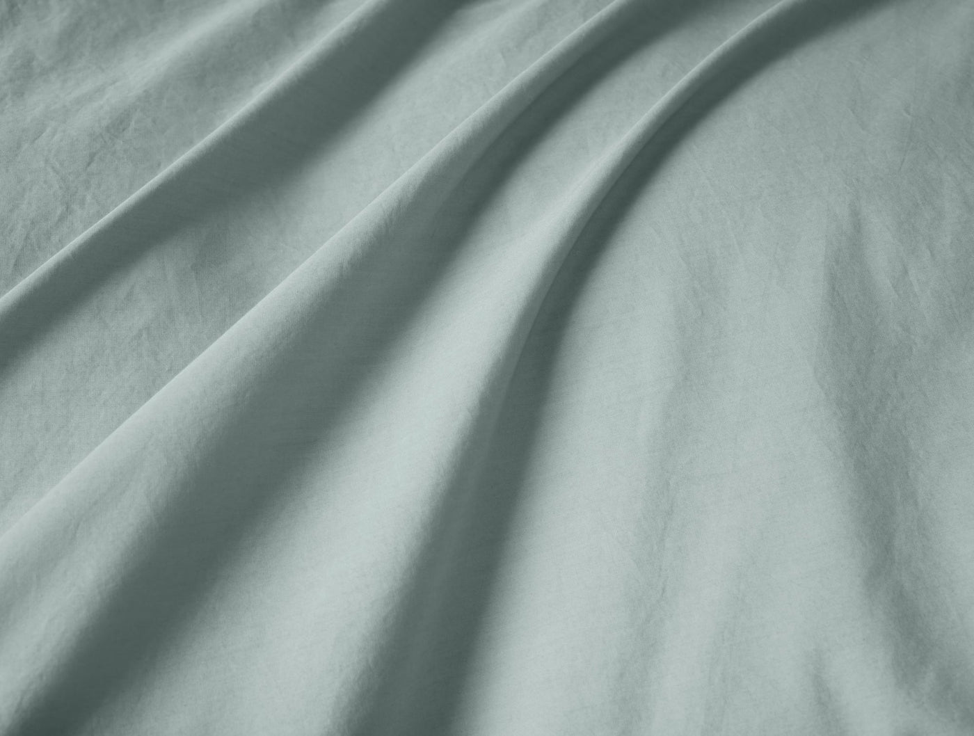 Close-up of sage green percale fabric with soft draping and subtle shadow detail.