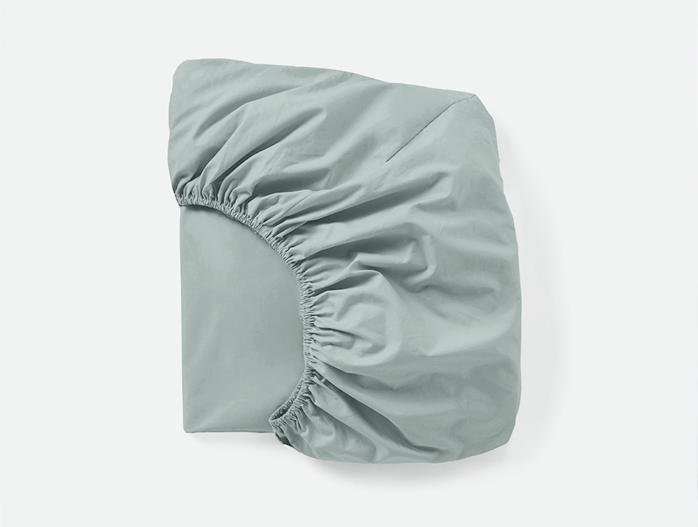 Coyuchi Refined Percale fitted sheet in sage, showing elasticated corners and smooth percale weave.