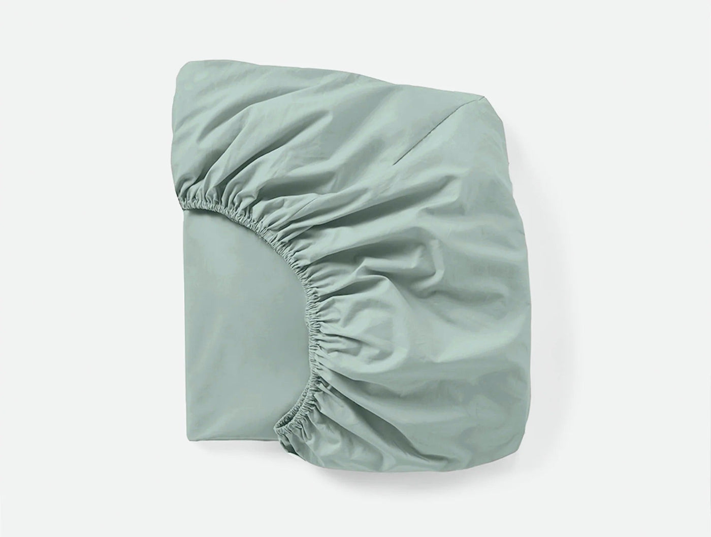 Sage green fitted sheet folded to show elasticized corner and smooth percale weave.